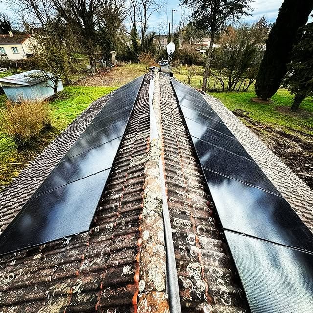Installation de panneaux photovoltaïques noirs alignés sur une toiture par Y.F. DEV, vue drone